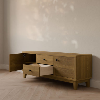 The Krovel Furniture Co.s Double Drawer, Double Door Media Cabinet in White Oak, handmade with formaldehyde-free hardwood in Portland, Maine, features three drawers and two cabinet doors. An open drawer and door show off its ample storage. It stands on a wooden floor against a plain wall with delicate shadows highlighting its elegance.
