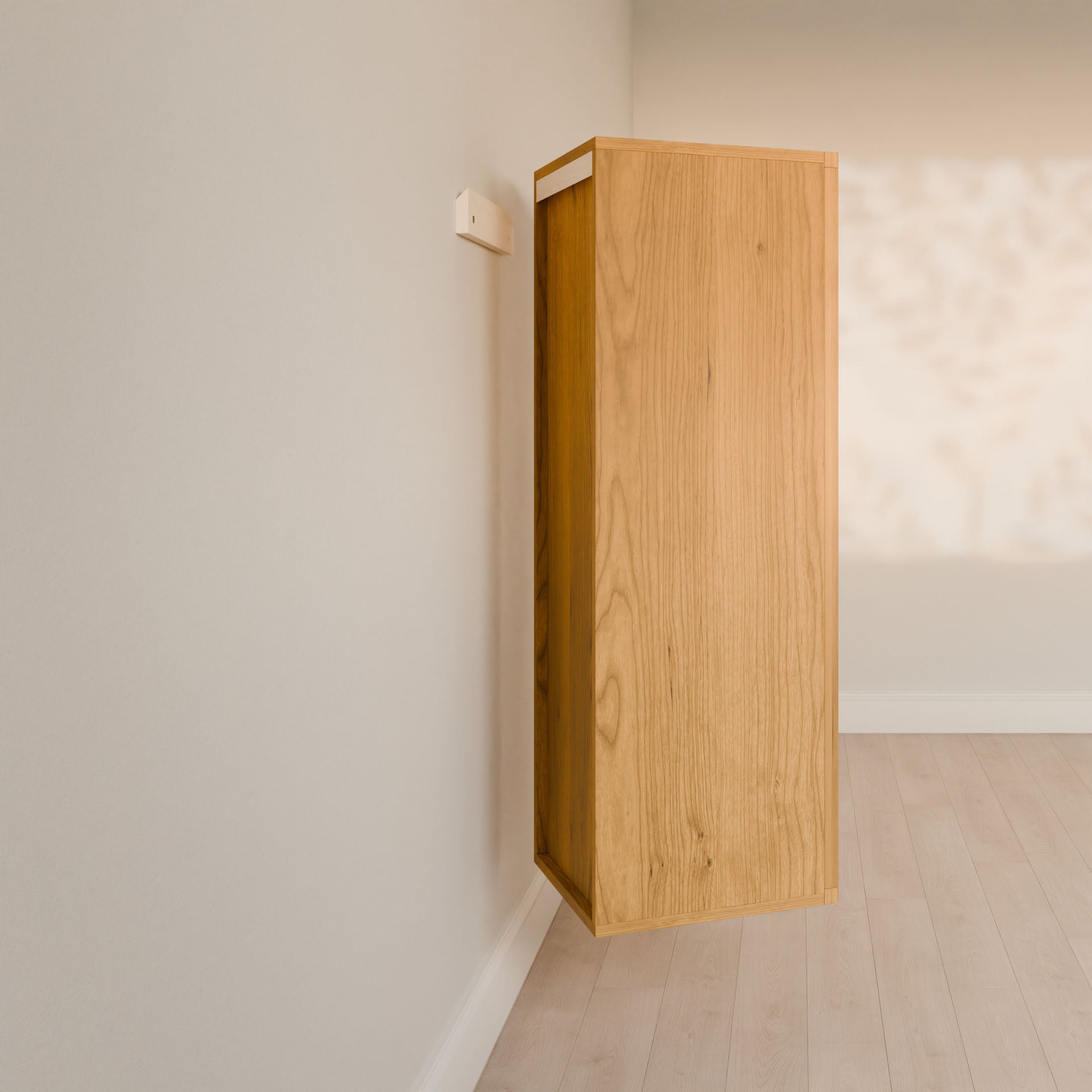 A Krovel Furniture Co. Double Drawer Linen Cabinet in Cherry, crafted from solid hardwood, is mounted on a beige wall with light wood floors. Its tall and narrow, casting a gentle shadow as natural light streams in, enhancing its sustainable design.