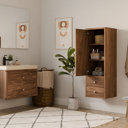 This bathroom features wooden cabinets and a potted plant, with abstract art adorning the walls. A woven basket holds towels beneath a floating vanity with sink and mirror. A patterned rug adds character, while Krovel Furniture Co.s customizable Double Drawer Linen Cabinet in Walnut provides flexible storage options.