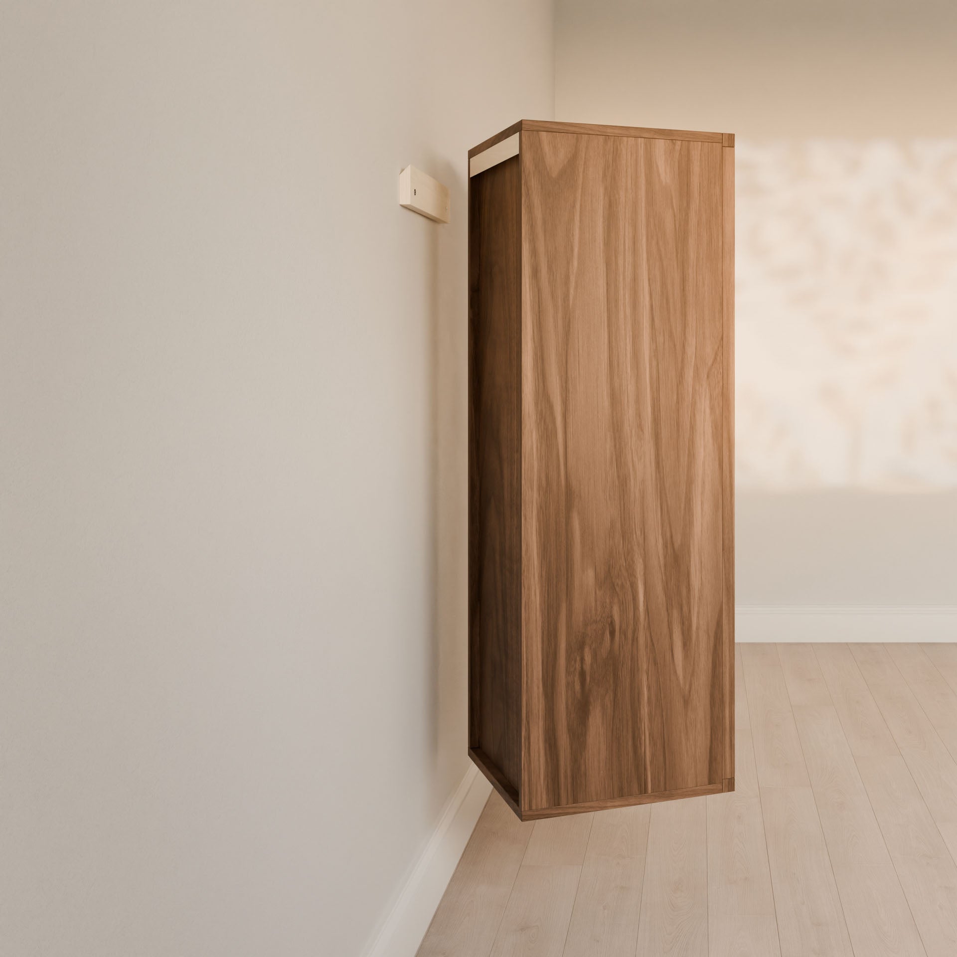 The Maine Made Double Drawer Linen Cabinet by Krovel Furniture Co. is mounted on a light wall above a pale wood floor, with sunlight casting leafy shadows that enhance the clean, minimal look of the space.