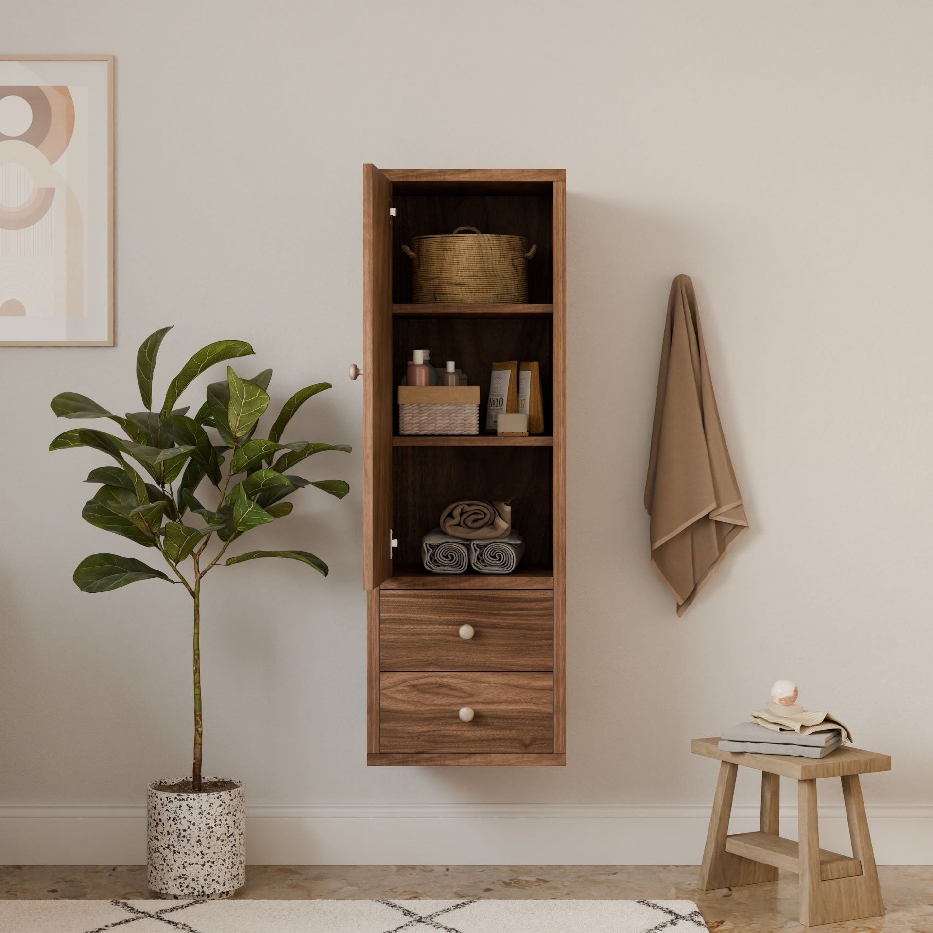 A minimalist bathroom features the Krovel Furniture Co.s Double Drawer Linen Cabinet in Walnut, available in customizable sizes for toiletries and towels. Nearby, a potted plant accents a wooden stool with a candle and soap dish. A beige towel hangs on a hook, while modern decor reflects sustainable principles.