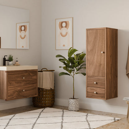 A minimalist bathroom showcases wooden cabinets, a white countertop with soap dispenser, and a potted plant. A Double Drawer Linen Cabinet in Walnut by Krovel Furniture Co. complements geometric art on the walls, with a wicker basket and beige rug anchoring the sustainable, neutral-toned space.