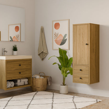 A modern bathroom featuring the Krovel Furniture Co. Maine Made Double Drawer Linen Cabinet, light wood accents, a green potted plant, a woven towel basket, a geometric rug, and abstract sun-and-landscape wall art.