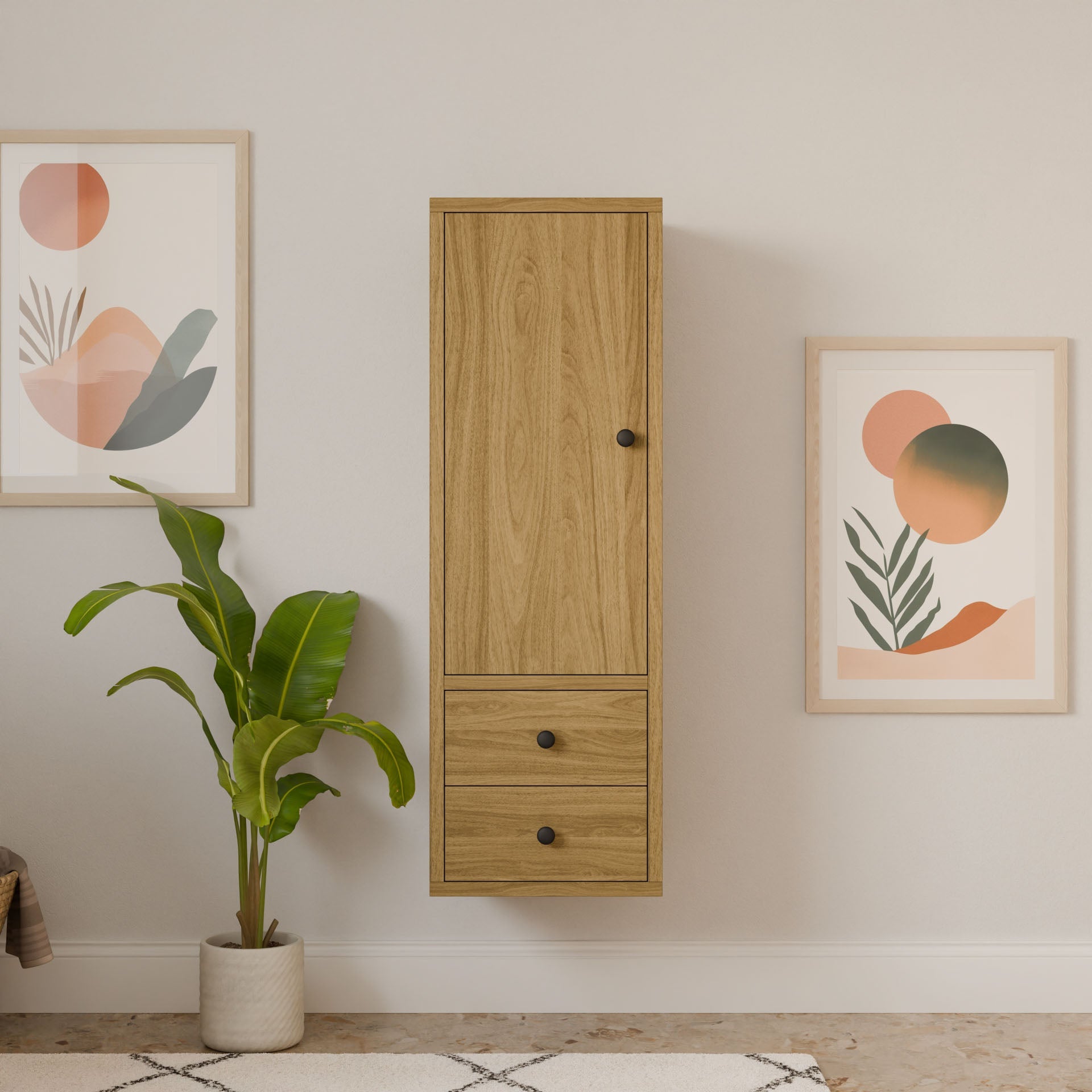 A minimalist room features Krovel Furniture Co.s Double Drawer Linen Cabinet in White Oak with a door and two drawers, flanked by abstract art prints. A green potted plant on the floor and a patterned rug enhance the serene, modern aesthetic.