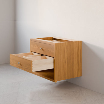 The Maine Made Double Drawer, Open Shelf Vanity by Krovel Furniture Co. features two open drawers with metal knobs and a sleek modern design. This hardwood floating vanity is available in custom sizes for your bathroom.