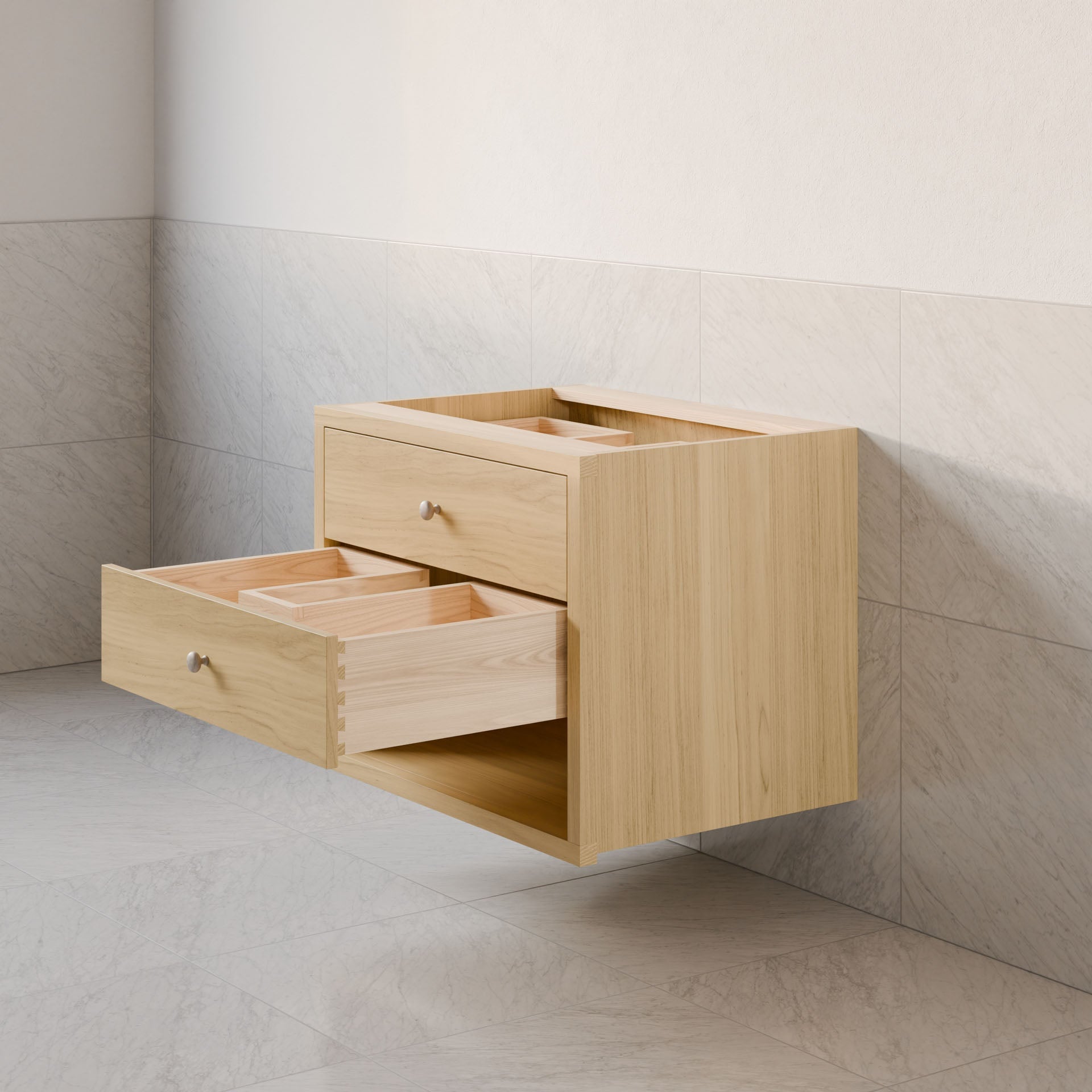 The Maine Made Double Drawer, Open Shelf Vanity by Krovel Furniture Co. is a light wood floating cabinet with two open drawers, round metal knobs, and interior compartments for organized storage, mounted on a tiled bathroom wall.