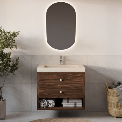 The Krovel Furniture Co. Maine Made Double Drawer, Open Shelf Vanity features a wood finish, integrated sink, and open shelf with rolled towels. Above is an oval backlit mirror; a basket of towels and a plant sit nearby against tiled walls.