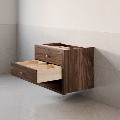 The Maine Made Double Drawer, Open Shelf Vanity by Krovel Furniture Co. features a modern hardwood design with two open drawers and light interiors, mounted on light gray tiled walls and floors.