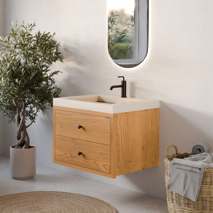 A bright, minimalistic bathroom features Krovel Furniture Co.'s Double Drawer Vanity in Cherry, topped with a rectangular white sink and black faucet. An oval mirror, potted plant, and woven basket of towels complete the tailored, modern look.
