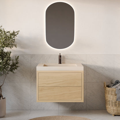A modern bathroom with a Krovel Furniture Co. Maine Made Double Drawer Vanity in light wood, an oval backlit mirror, a tiled wall, a plant on the left, and a woven basket with towels on the right.