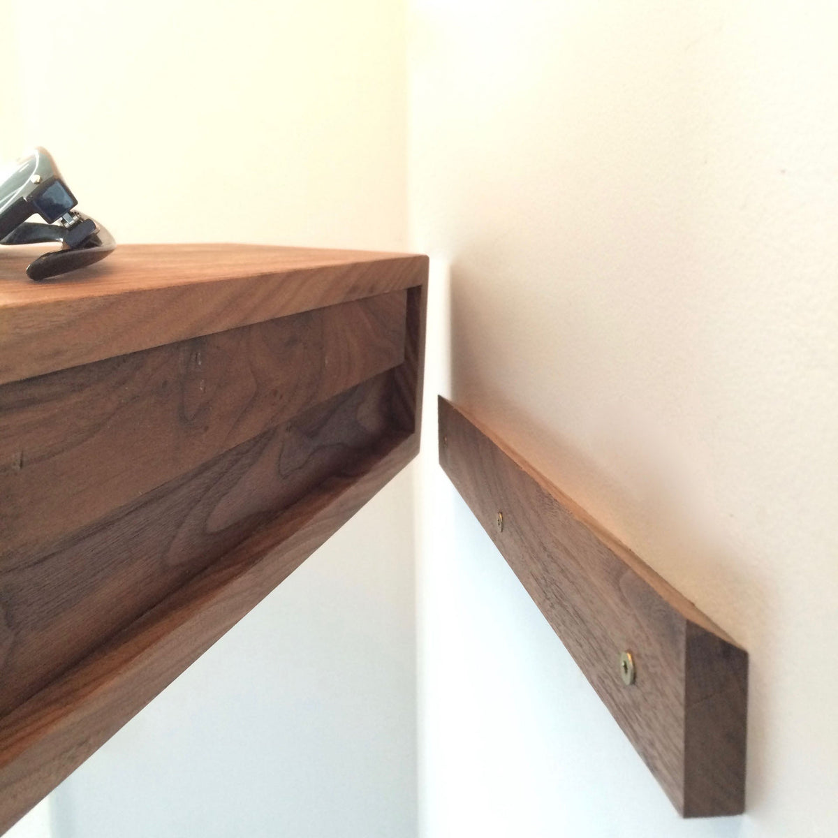 A close-up of the Krovel Entryway Organizer in Walnut being installed, featuring a wooden mounting bracket secured to a white wall with two screws. Ideal as a floating entryway organizer or handmade key holder.