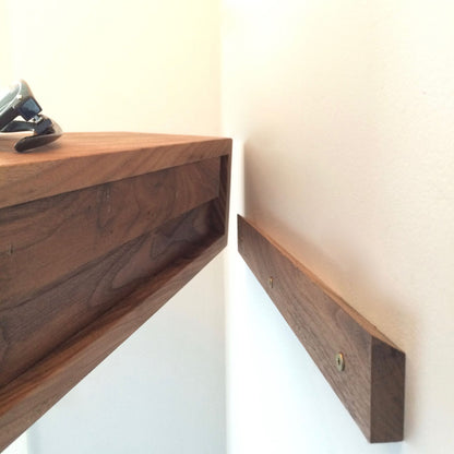 A close-up shows the Krovel Hardwood Entryway Organizer being aligned with a wooden wall bracket for mounting, screws visible in the bracket, and a watch resting on top of the organizer.