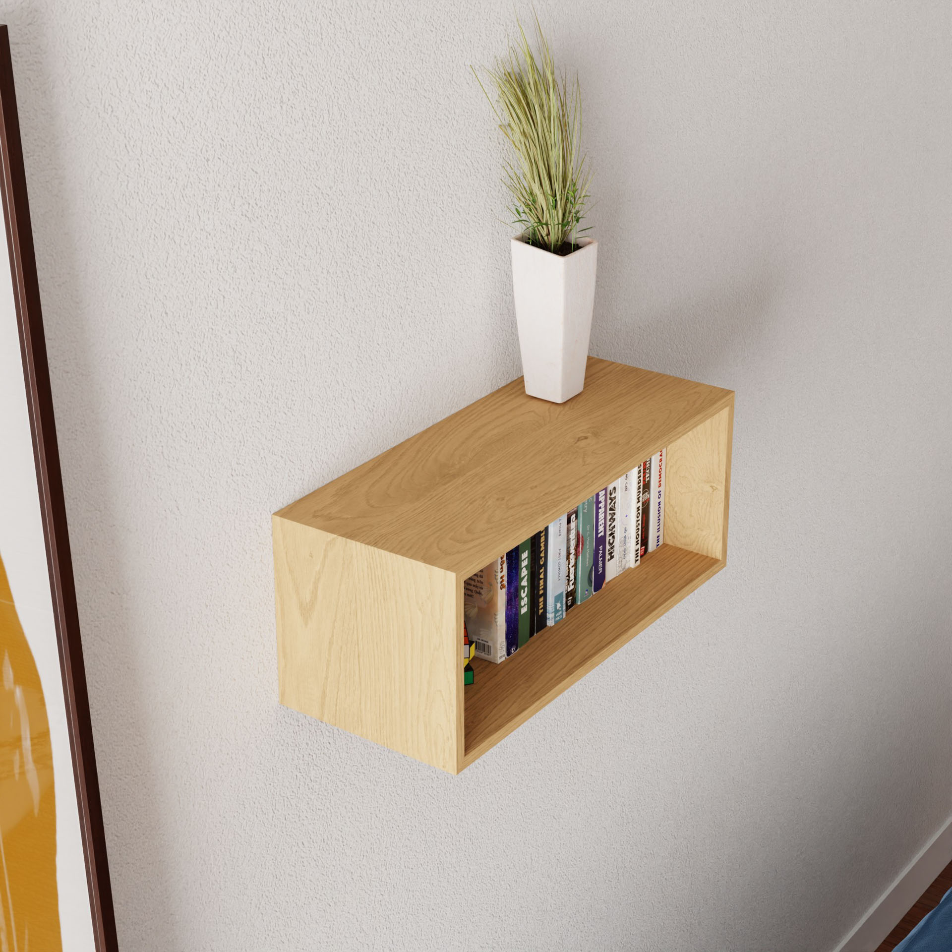 A Krovel Floating Bookshelf in Maple elegantly adorns the light-colored wall, displaying books neatly. A small white planter with a green leafy plant sits on the shelf, while framed artwork peeks in from the left.
