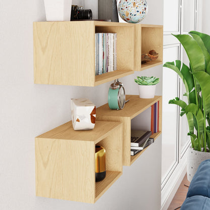 Krovel's Floating Bookshelf in Maple, crafted from solid American hard maple, showcases books, a clock, decorative items, and a small plant by a tall window. Next to a navy blue sofa, it adds a cozy, modern touch to the living area.