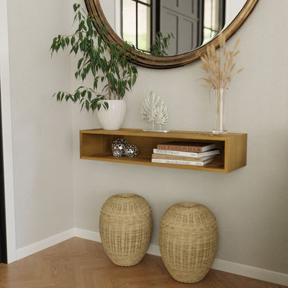The Krovel Hardwood Floating Console Table is mounted on a pale wall beneath a round mirror, styled with books, decor, and dried flowers; two woven baskets are placed on the floor below.