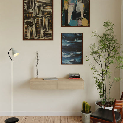 A modern room with a maple floor features a Krovel Floating Desk in American Cherry, holding books, a lamp, and potted plants. Abstract art pieces adorn the wall, while a tall floor lamp stands beside a potted plant and chair, enhancing the space's inviting elegance.