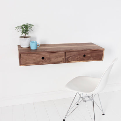 A Krovel Hardwood Floating Desk with a sleek chair sits beneath a shelf featuring a lush plant, creating a stylish and space-saving workspace.