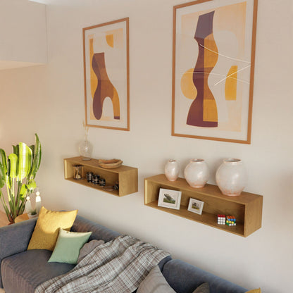 A cozy living room with a gray sofa, yellow and green cushions, a patterned throw, the Krovel Floating Display Case in Cherry holding vases, framed photos, decor items, and two abstract art prints on the wall.