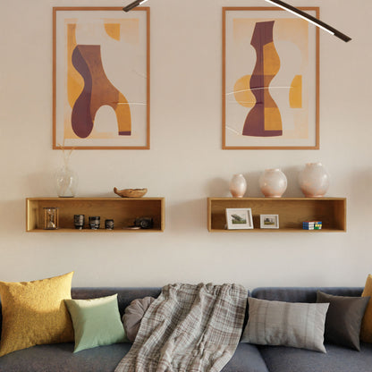 A modern living room features a gray sofa, colorful pillows, and a plaid throw. Above, Krovel Hardwood Floating Display Cases showcase vases, framed photos, and decor, while two earthy abstract art prints hang on the wall.