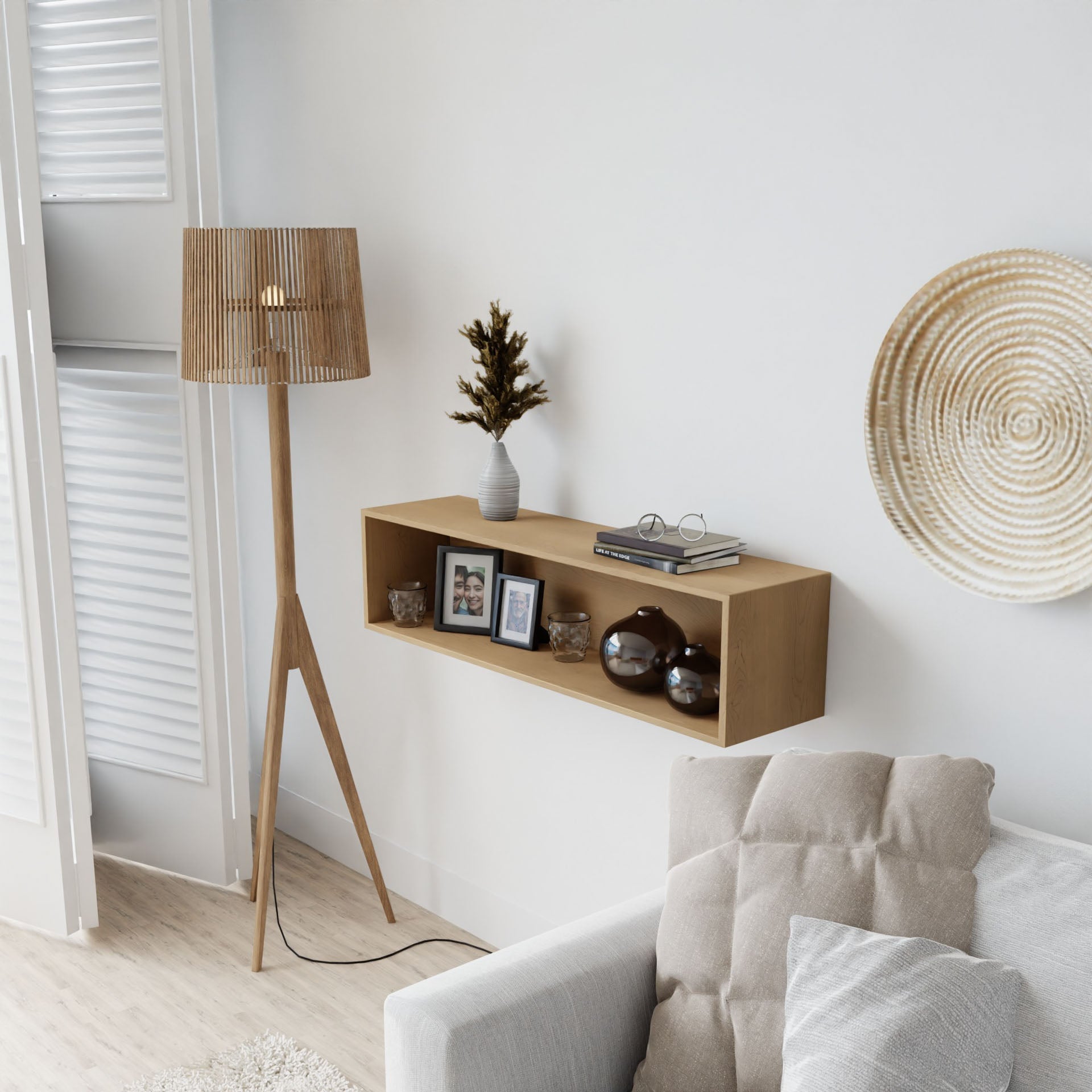 A modern living room with a beige couch, wooden tripod floor lamp, Krovel Hardwood Floating Display Cases showcasing framed photos, vases, and a plant, plus a decorative woven wall plate on a white wall.