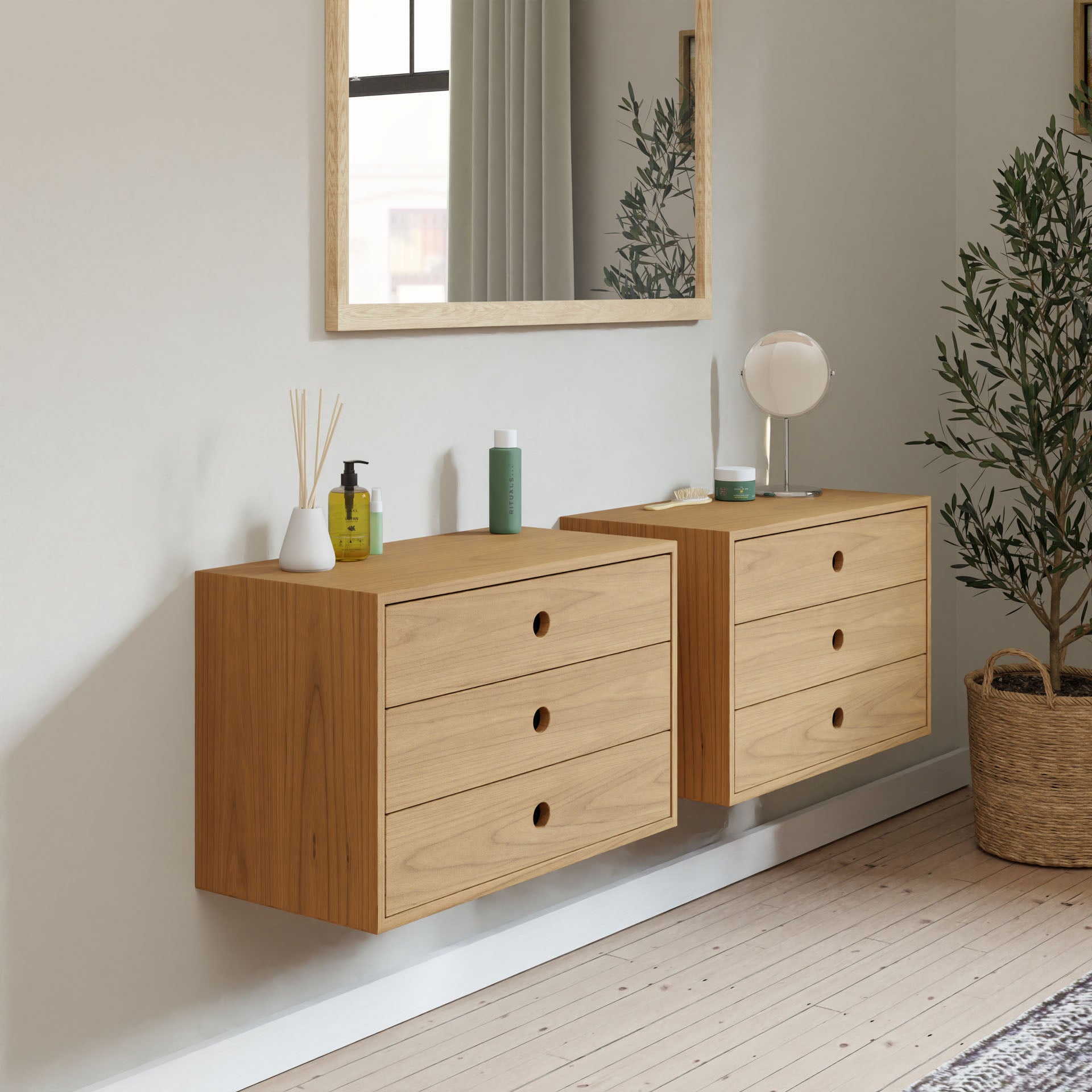 Minimalist bedroom with a sleek oversized Krovel Floating Dresser in Cherry and a large mirror above. Bottles and reed diffusers adorn the dresser. A tall plant in a woven basket decorates the corner, while natural light enhances the neutral color palette.