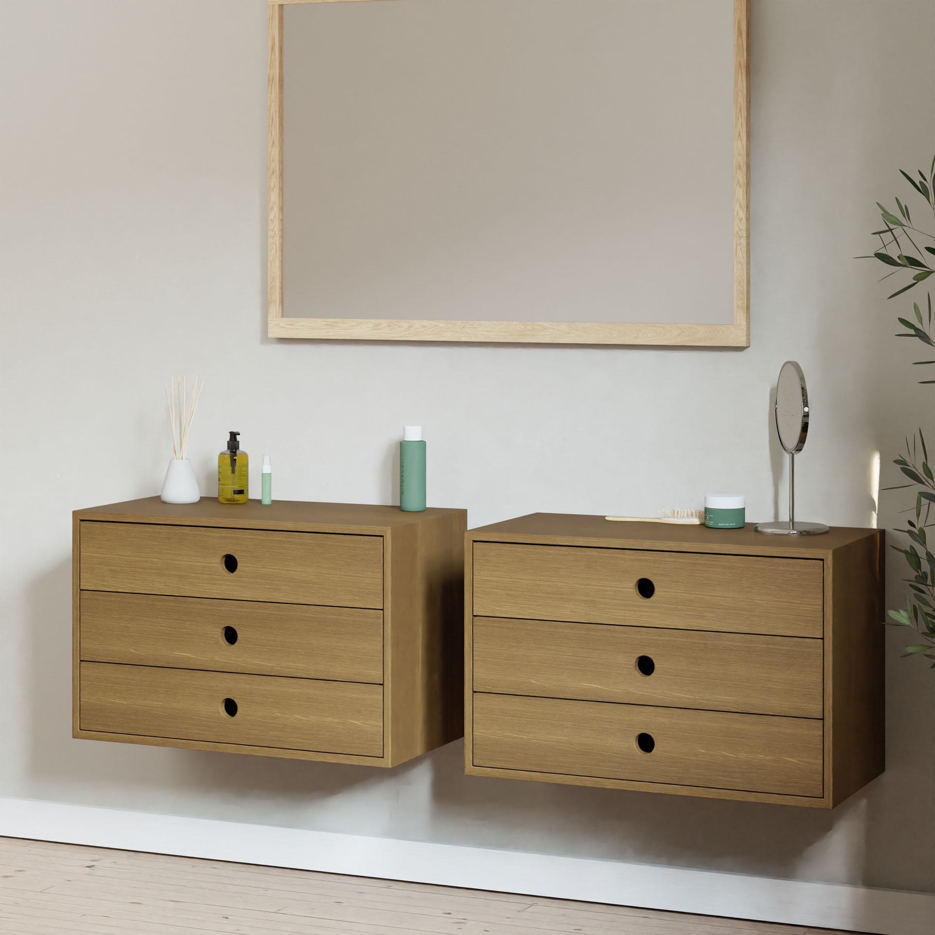 Two Krovel Hardwood Floating Dressers with three drawers each are mounted beneath a large rectangular mirror. Toiletries and a small round mirror sit on top, with a plant partially visible to the right.