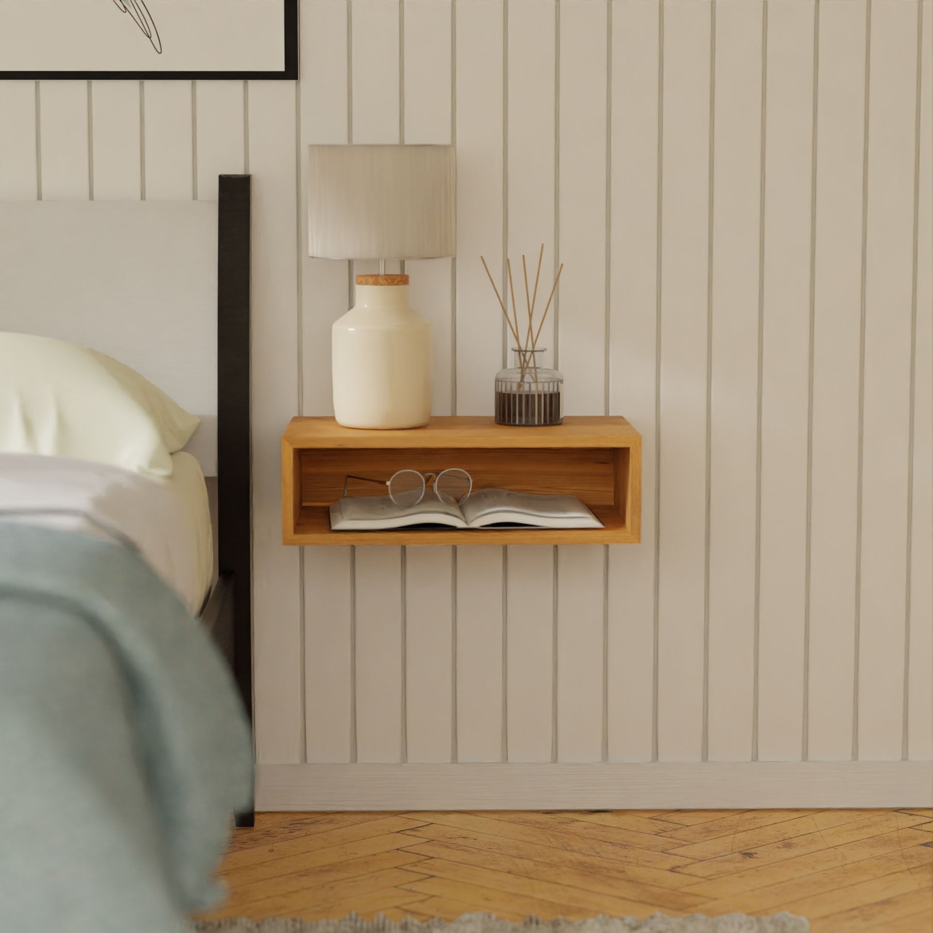 A minimalist bedroom showcases a Floating Nightstand in Cherry by Krovel, elegantly mounted with a French cleat. It supports a cream-colored lamp, a glass jar with reed diffuser sticks, glasses, and an open book. In the background, vertical wood paneling is visible alongside part of a bed dressed in white linens.#configuration_single-shelf