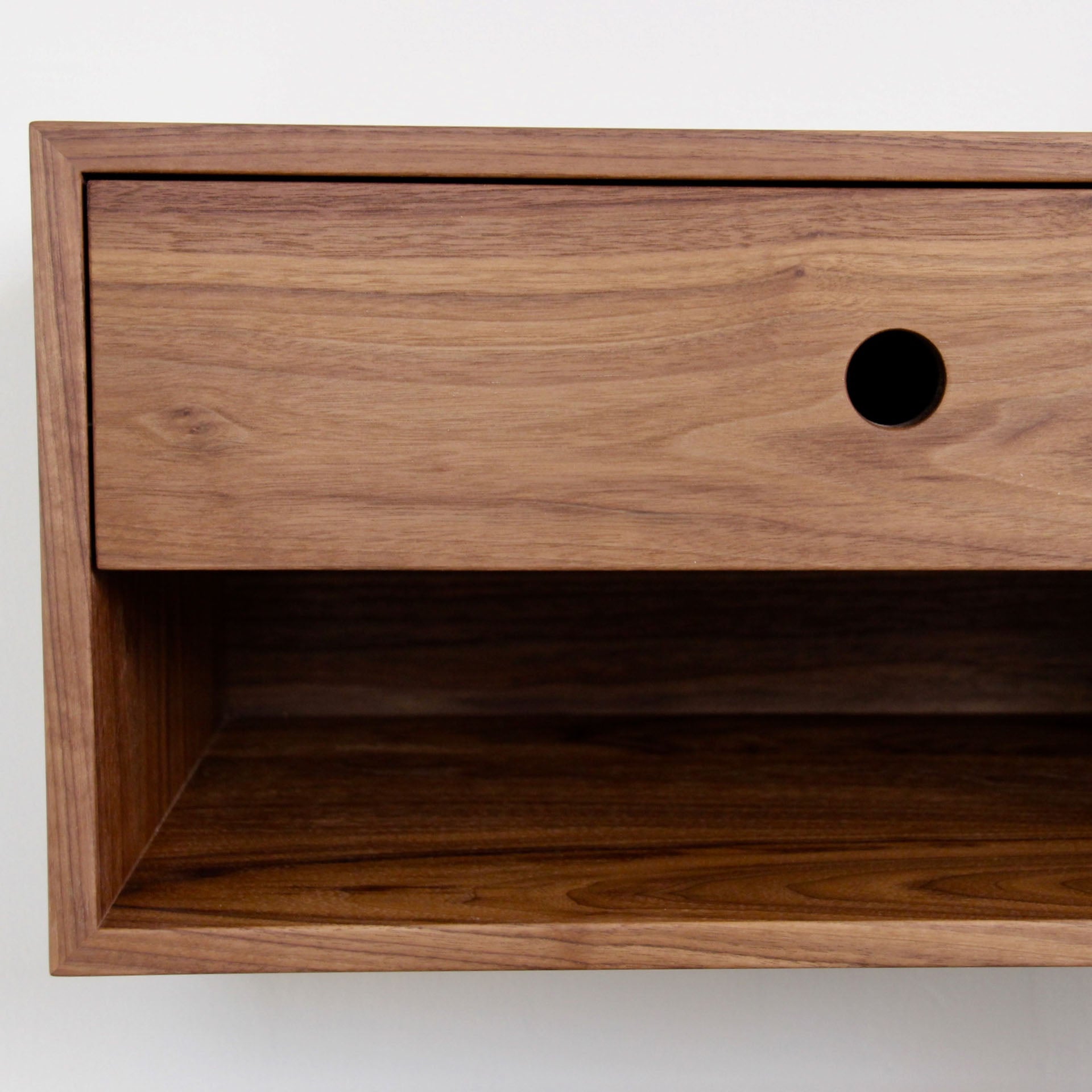 A close-up of the Krovel Hardwood Double Floating Nightstand, crafted from solid hardwood, with two drawers featuring round black pull holes and open compartments below, shown against a white background.
