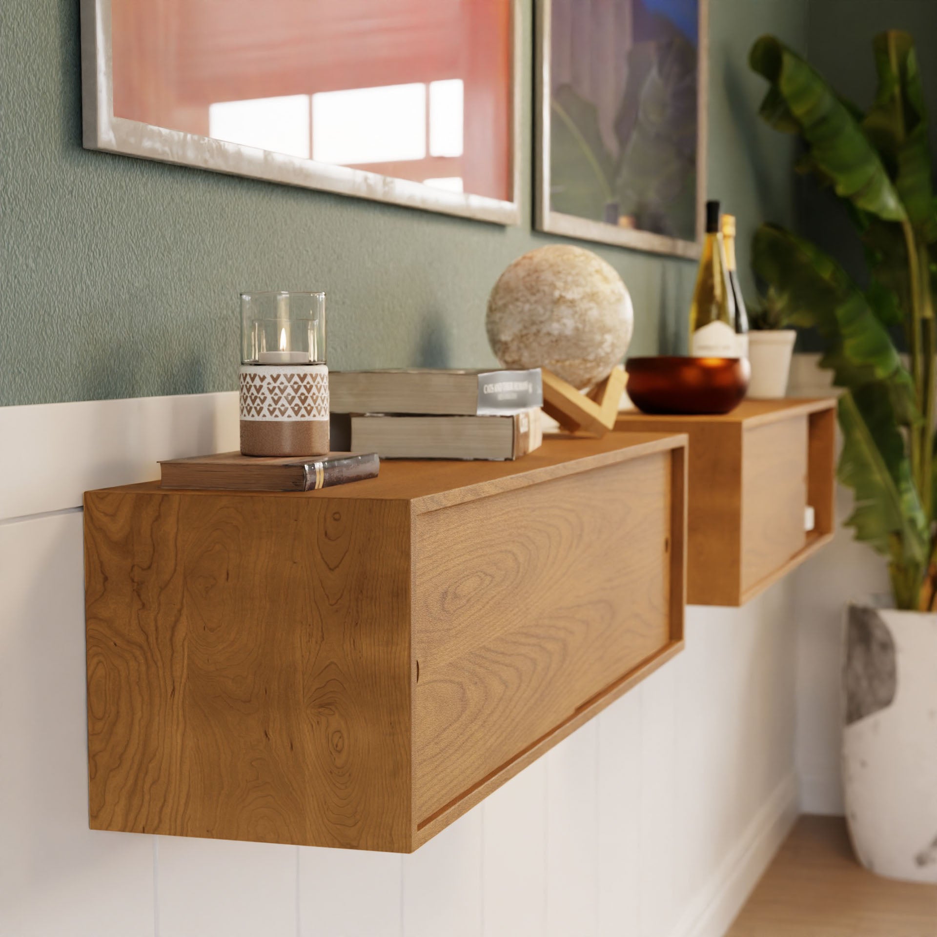 Krovel's Floating Storage Cabinet in Cherry, with a candle, glass, books, a globe, and wine bottles on display against a green wall and large plant backdrop, creates a serene atmosphere.
