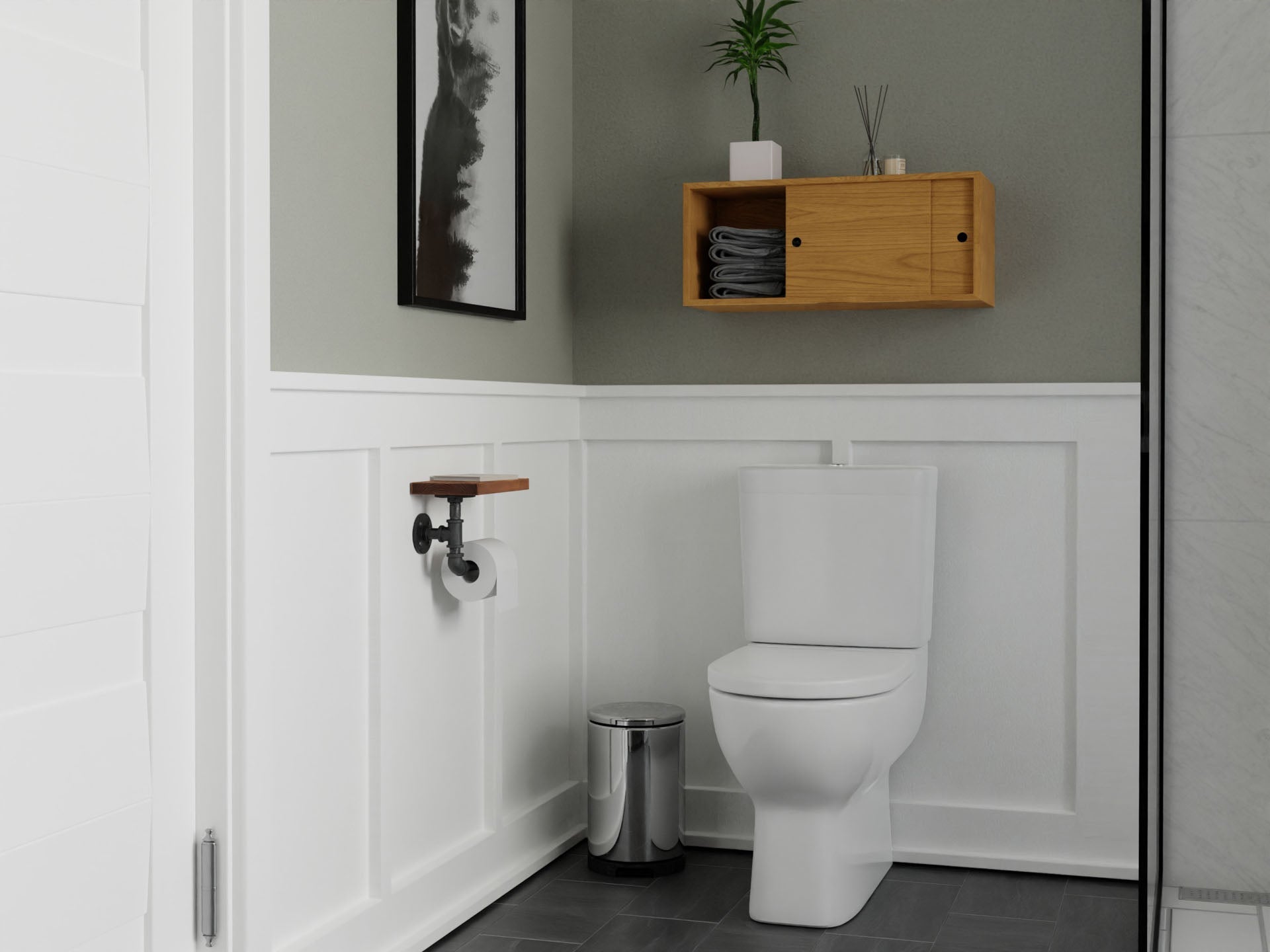 A modern bathroom features a white toilet, Krovel's Floating Storage Cabinet in Cherry with rolled towels and a potted plant, a silver trash can, and a toilet paper holder beneath framed abstract artwork. The walls are half-paneled in gray with warm American Cherry accents.