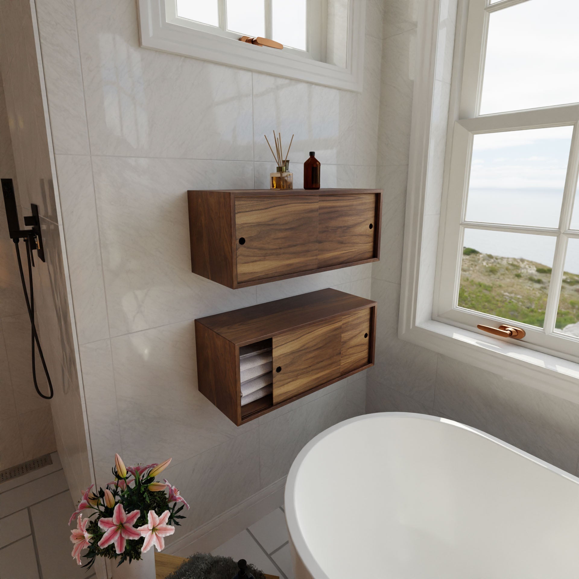 A modern bathroom boasts a white freestanding bathtub near large windows with coastal views. Two Krovel Floating Storage Cabinets in Walnut complement the space, while pink flowers adorn a small table. Sunlight illuminates this handmade haven.