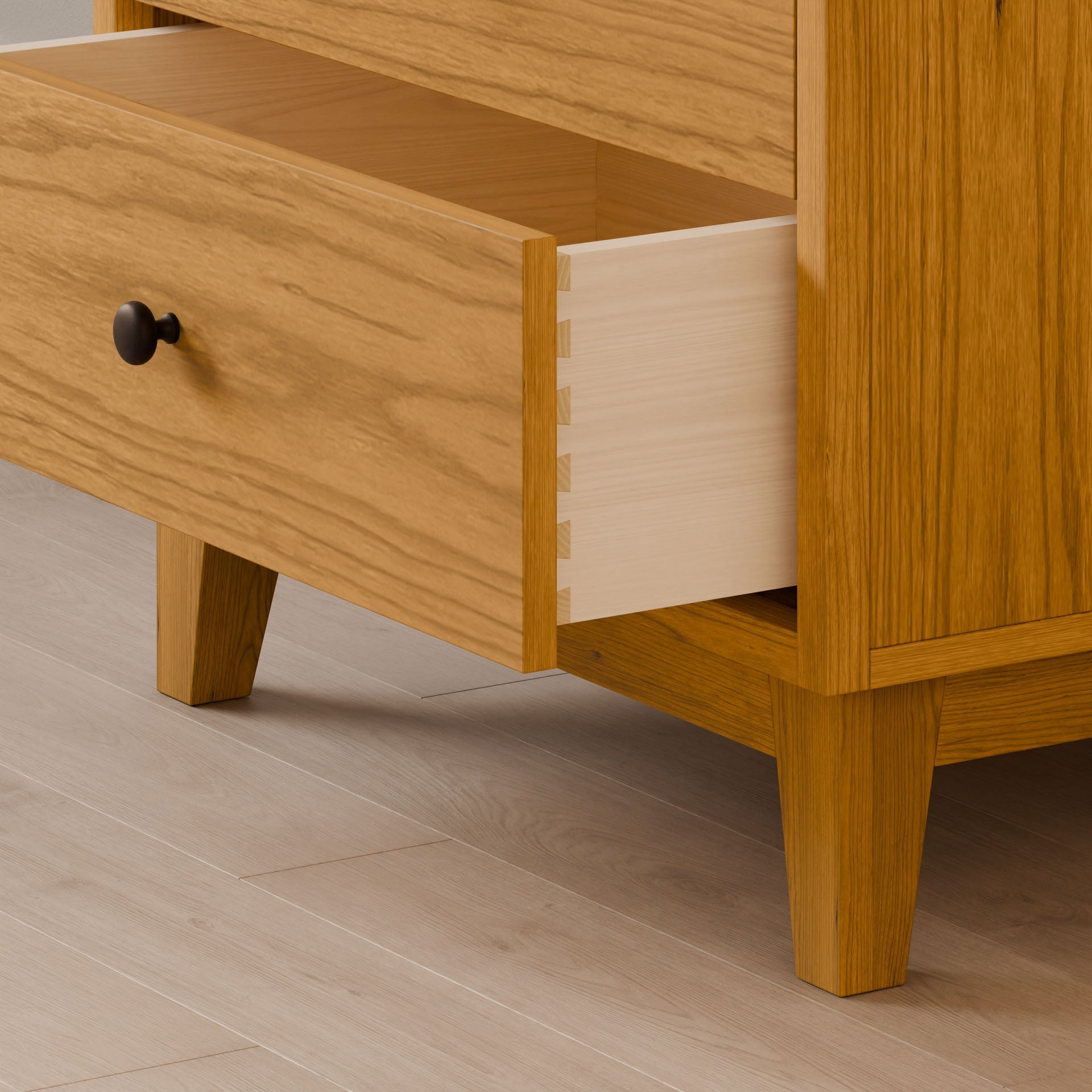 Open the cherry drawer of a Krovel Furniture Co. Four Drawer Dresser, featuring dovetail joints and elegant handmade construction. The dressers sustainable design is beautifully highlighted against the light-colored wood floor, with black knobs adding a touch of contrast.