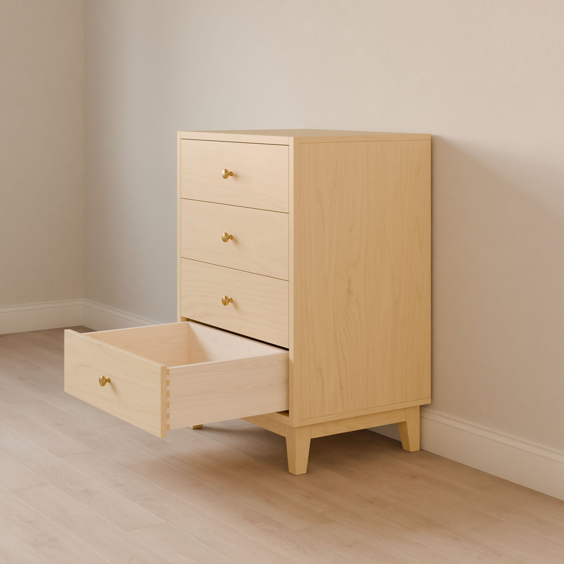 The Four Drawer Dresser in Maple from Krovel Furniture Co. stands on a wooden floor against a beige wall. Its four drawers with brass handles, three closed and one slightly open, highlight the minimal decor and sustainable construction of this handmade piece.