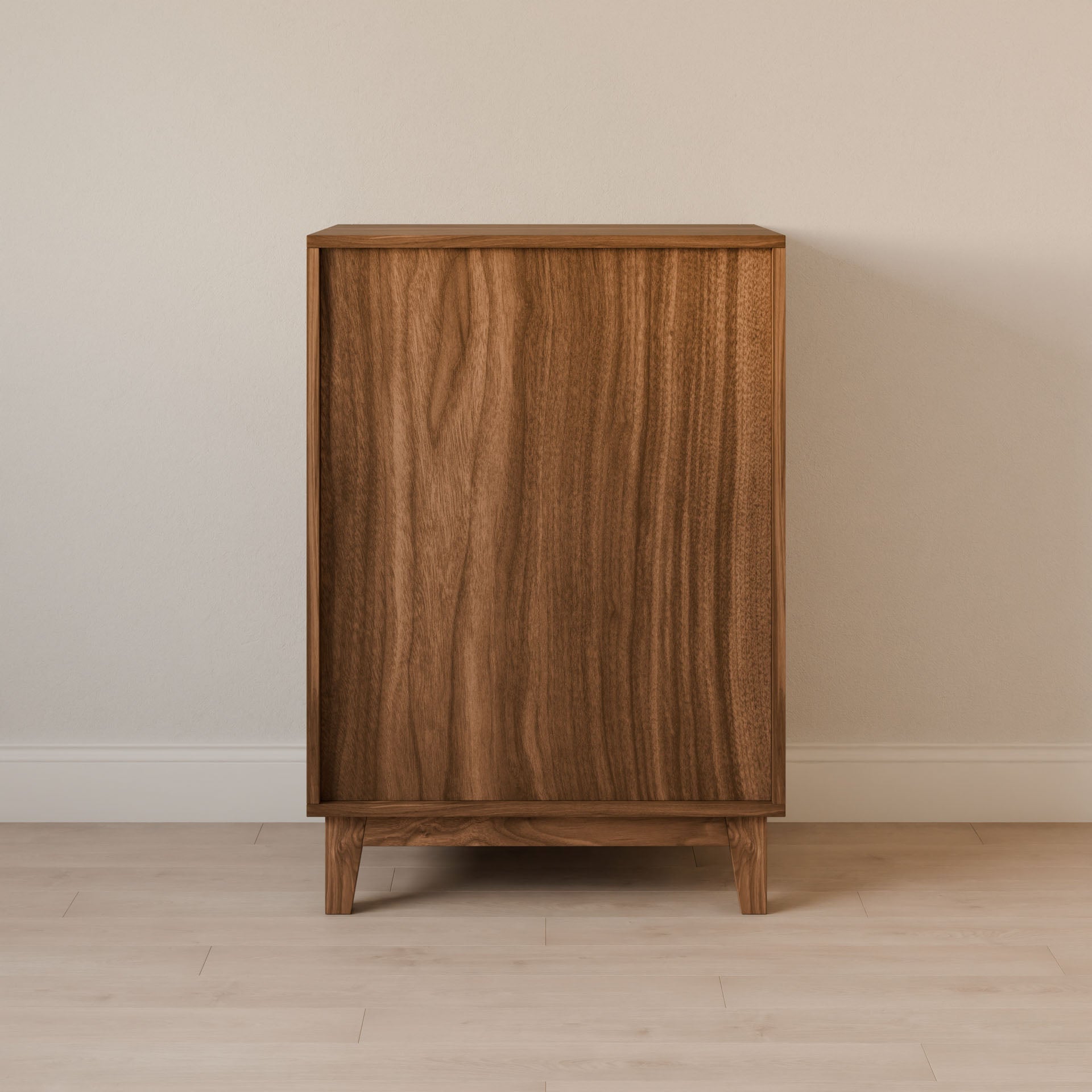 The Krovel Furniture Co. Maine Made Four Drawer Dresser, handcrafted in Portland, Maine, showcases a minimalist solid wood design with a smooth natural finish and clean lines, standing against a light wall and floor without visible handles or adornments.