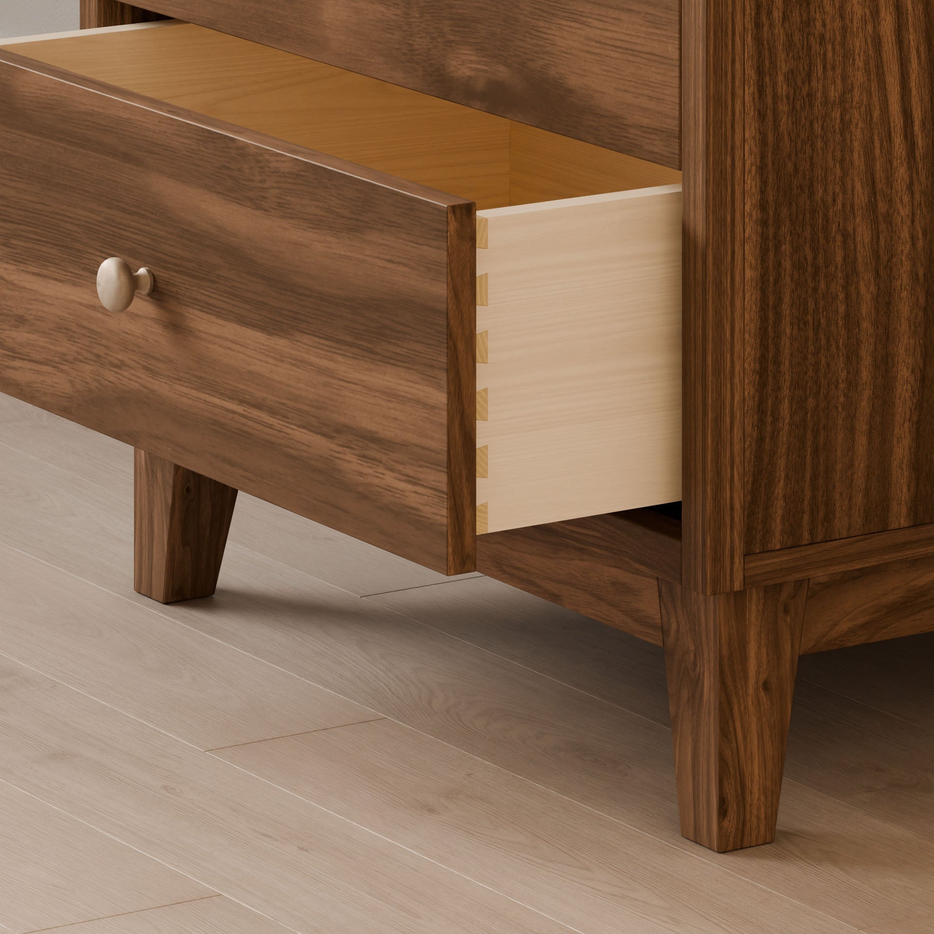 The open drawer of the Krovel Furniture Co.s Four Drawer Dresser in Walnut exhibits dovetailed solid Maple craftsmanship, with a simple round knob. Its polished wooden elegance stands on a light-colored hardwood floor, highlighting sustainable construction.