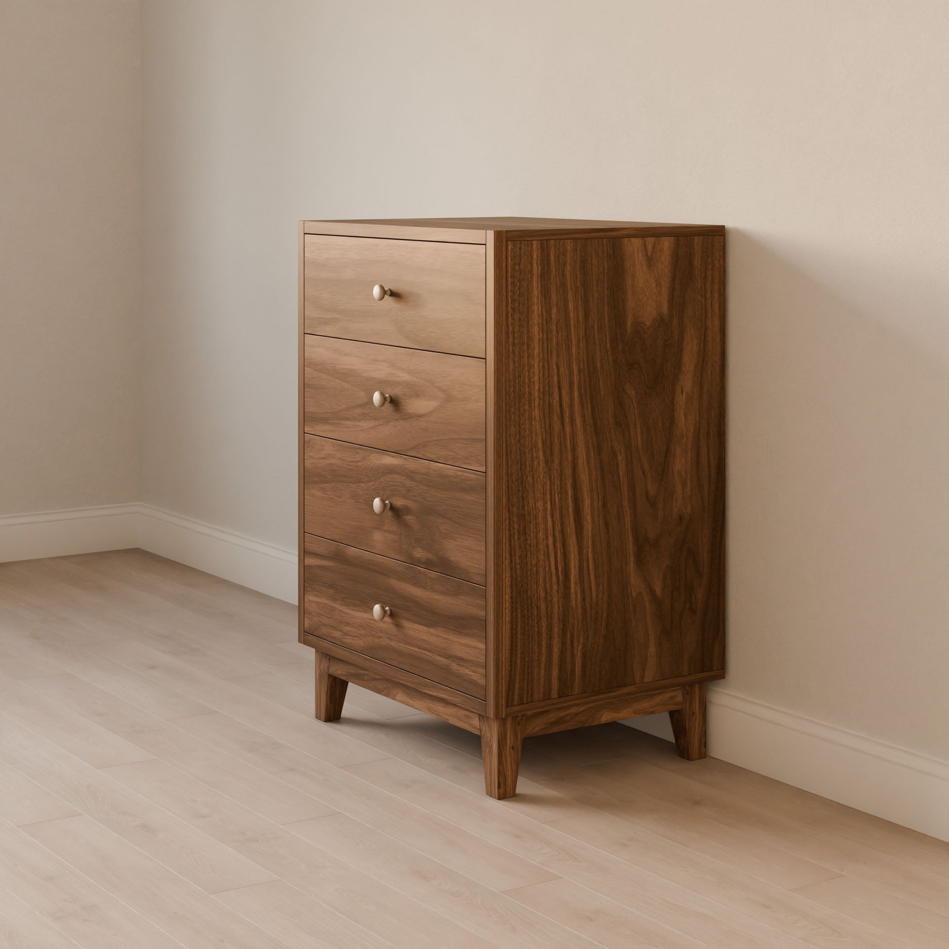 The Krovel Furniture Co. Four Drawer Dresser in Walnut, crafted from premium cabinet-grade plywood with dovetailed solid maple drawers, sits on four short legs. It features round metal knobs and complements the rooms light-colored walls and wood flooring.