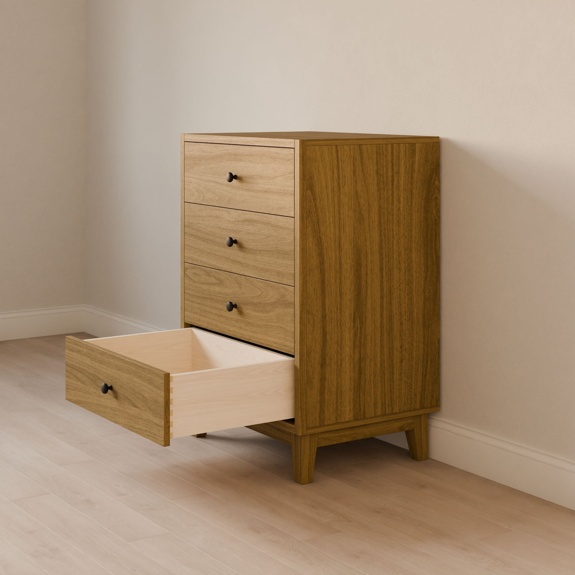 The Maine Made Four Drawer Dresser by Krovel Furniture Co. stands against a light wall, with its solid wood frame and four drawers visible—the bottom drawer is open to show the light wood interior. The floor beneath is also a light wood.
