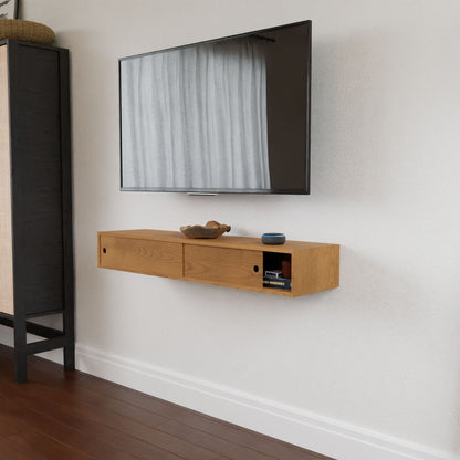 A wall-mounted flat-screen TV is positioned above the Krovel Hardwood Media Console, which holds a bowl, small round object, and books—ideal for a media room with white walls, wooden floors, and a partial tall cabinet visible on the left.