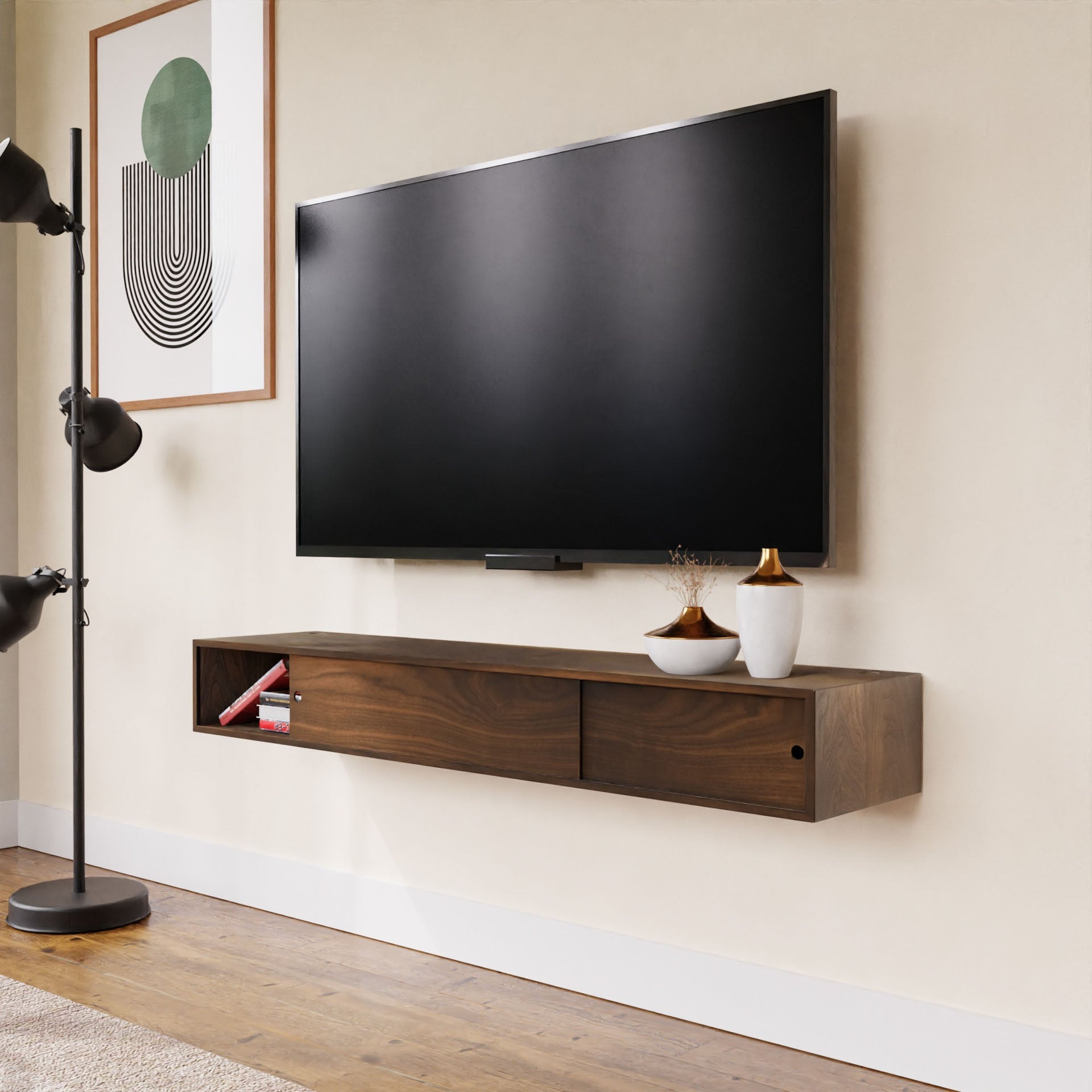 A modern living room includes a flat-screen TV above a Krovel Media Console Table in Walnut, which holds decorative vases and books. A black floor lamp stands on the left, and abstract artwork decorates the walls. The space is completed by light wood flooring.
