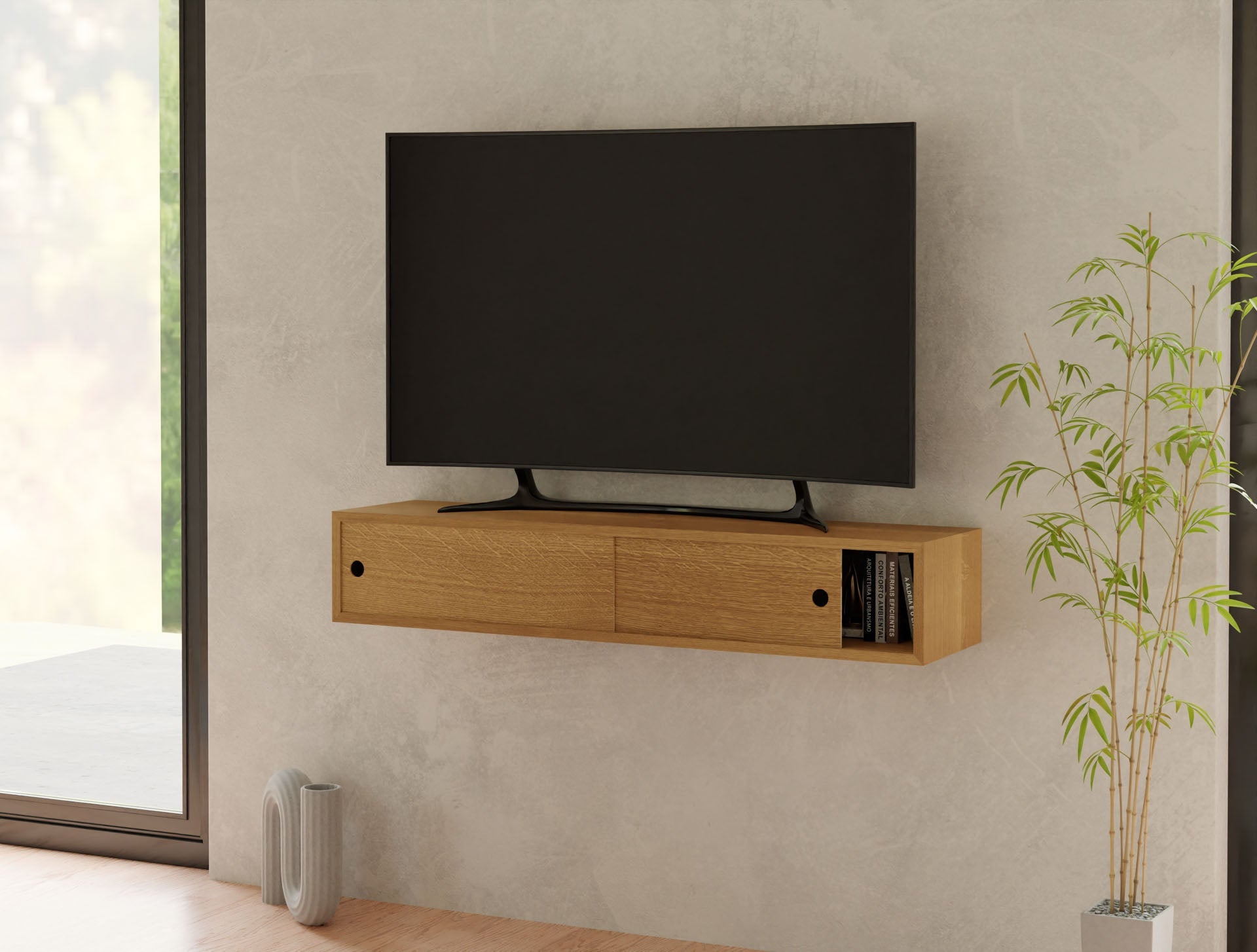A modern living room highlights a Krovel Media Console Table in White Oak, displaying a flat-screen TV. Its sleek design features two drawers and a small shelf with a book. Nearby, a potted bamboo plant provides greenery by the large window on the left.
