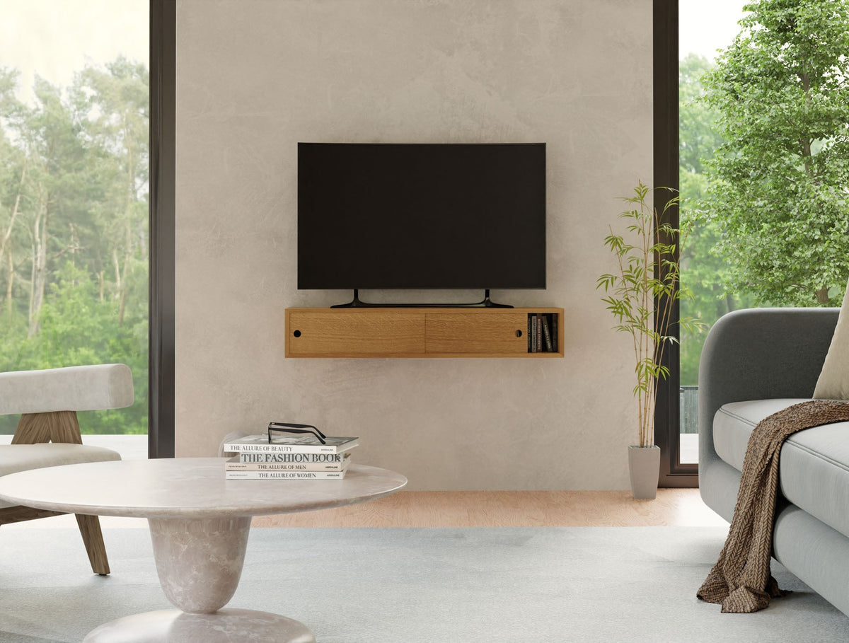 A modern living room with the Krovel Media Console Table in White Oak beneath a wall-mounted TV, a gray sofa, round marble coffee table, small plant, and large windows—an ideal setup for stylish media room furniture.