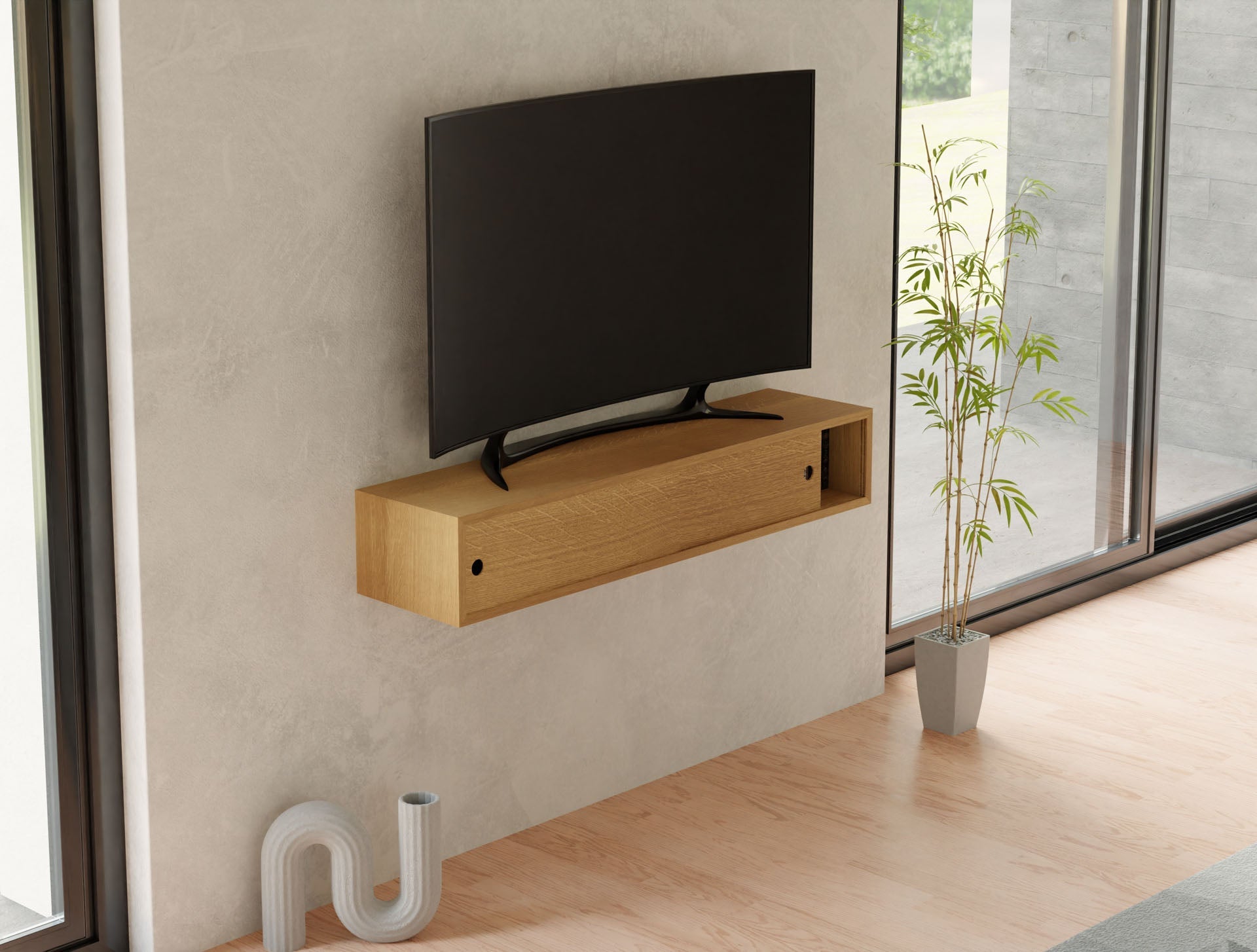 A modern living room showcases a flat-screen TV on a beige wall above a Krovel Media Console Table in White Oak. Below is a hand-finished wooden shelf, and a small potted bamboo plant sits by large glass doors offering an outdoor view.