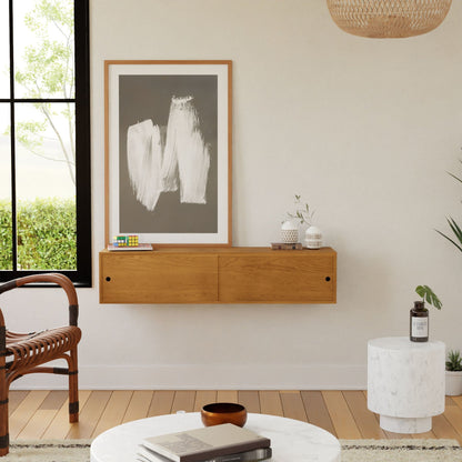 A modern living room features the Krovel Hardwood Oversized Media Console with small decor, abstract art in a wooden frame, a round marble side table, a rattan chair, and a large window letting in natural light.