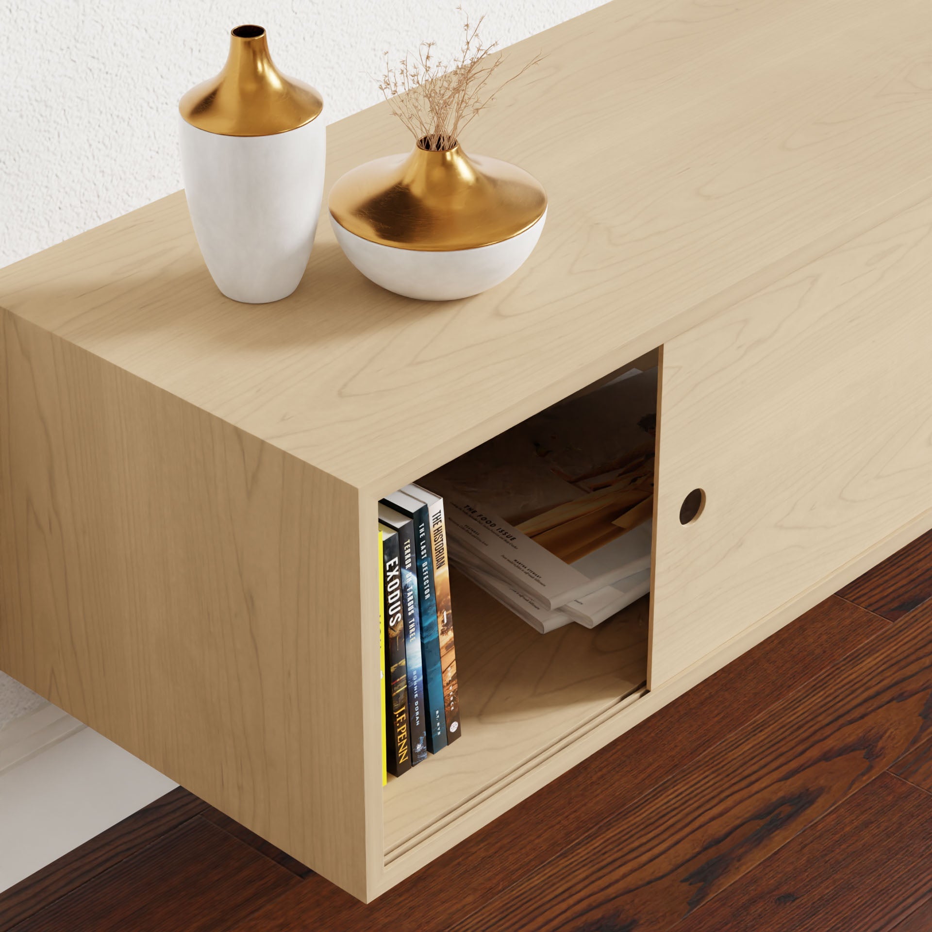 The stylish Oversized Media Console Table in Maple by Krovel features a sliding door, partially open to display books and magazines. Two decorative vases—one gold and white, the other filled with dried flowers—adorn the top, while the polished dark wood floor complements its elegance.