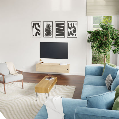 Modern living room with light walls, blue sofa, wooden coffee table, armchair, large plant, and four abstract black-and-white art pieces. Sunlight streams in above a Krovel Hardwood Oversized Media Console beneath a wall-mounted TV.
