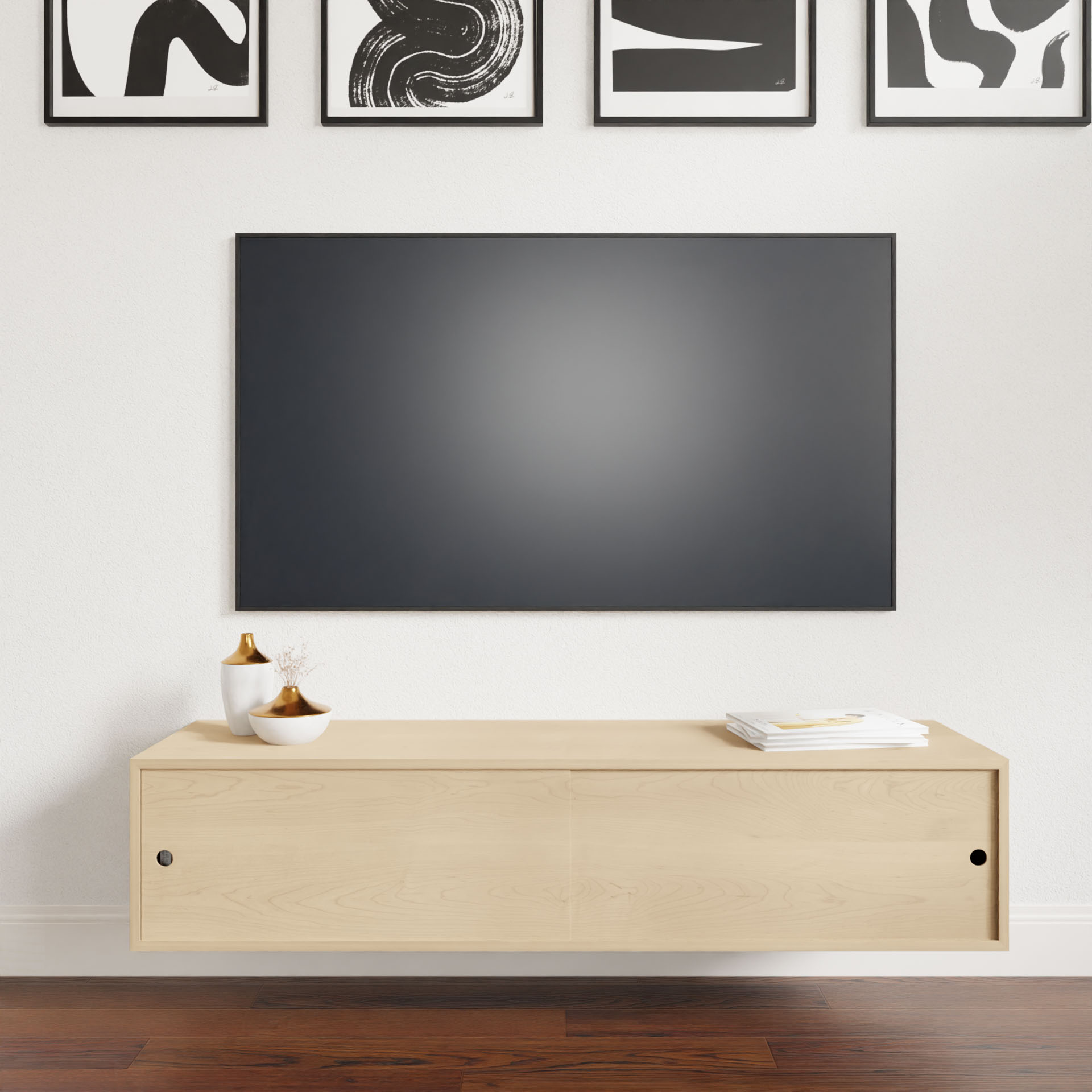 A modern living room with a large blank TV on a white wall, the Krovel Hardwood Oversized Media Console below, two gold and white vases, a small plant, stacked magazines, and abstract black-and-white art hanging above.