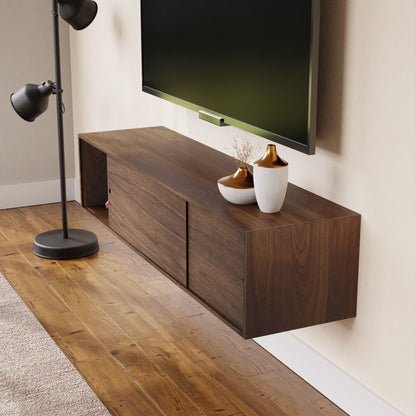 A modern living room features a Krovel Oversized Media Console Table in Walnut, adorned with decorative vases. A flat-screen TV is mounted above, and a black floor lamp stands on hardwood flooring next to a carpeted area.