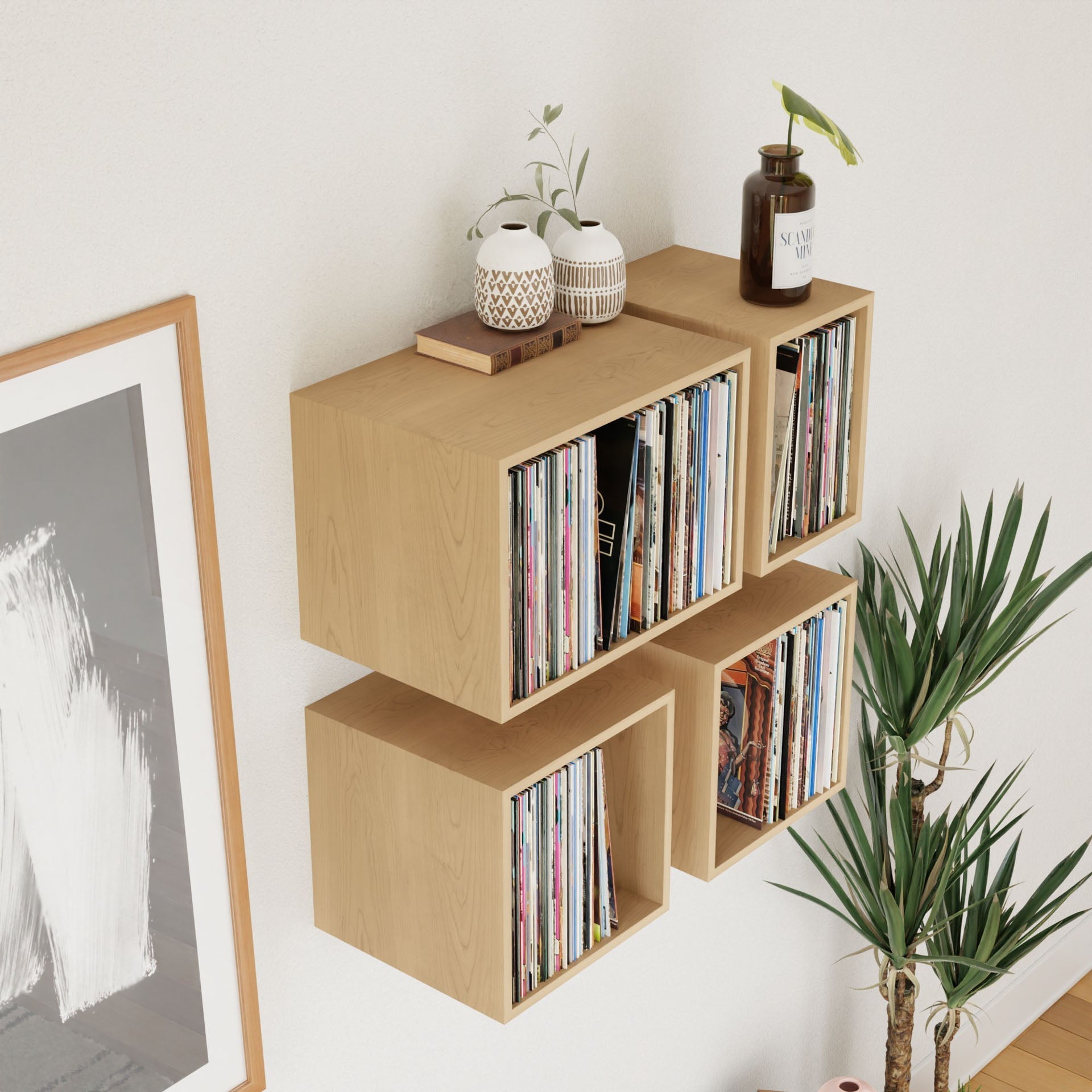Krovel's Record Storage Shelves in Maple showcase vinyl records, small potted plants, and vases. A framed abstract art piece is partially visible on the left with a tall plant nearby, creating a minimalist, modern setting.