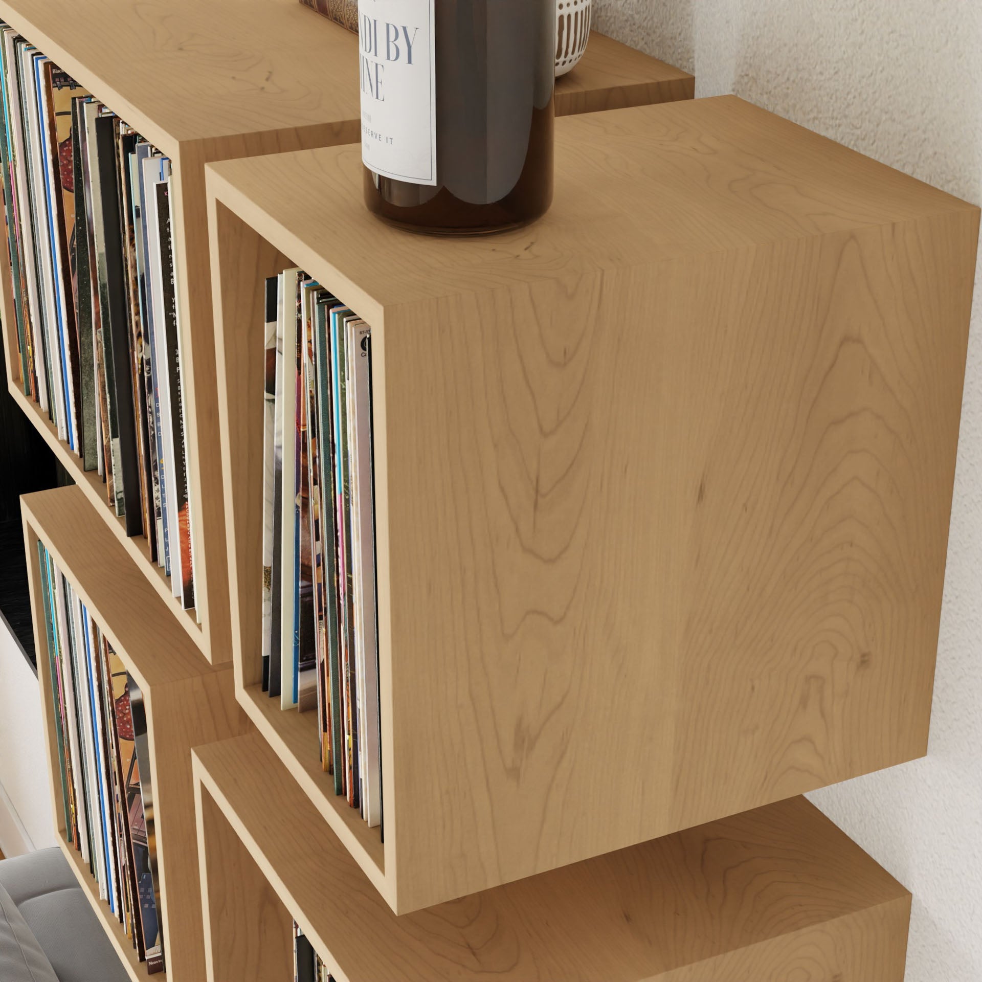 Maple Record Storage Shelves by Krovel mount to the wall, creating a minimalist look. These elegant floating shelves hold vinyl records and feature rich grain for added warmth. A BY SCENT candle sits atop the upper shelf, completing this sophisticated design.