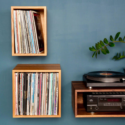 A modern blue wall features krovel-dev's Record Storage Shelves in White Oak, showcasing vinyl records with a vintage cassette player and turntable. A touch of greenery adds decoration, seamlessly blending classic and contemporary styles.